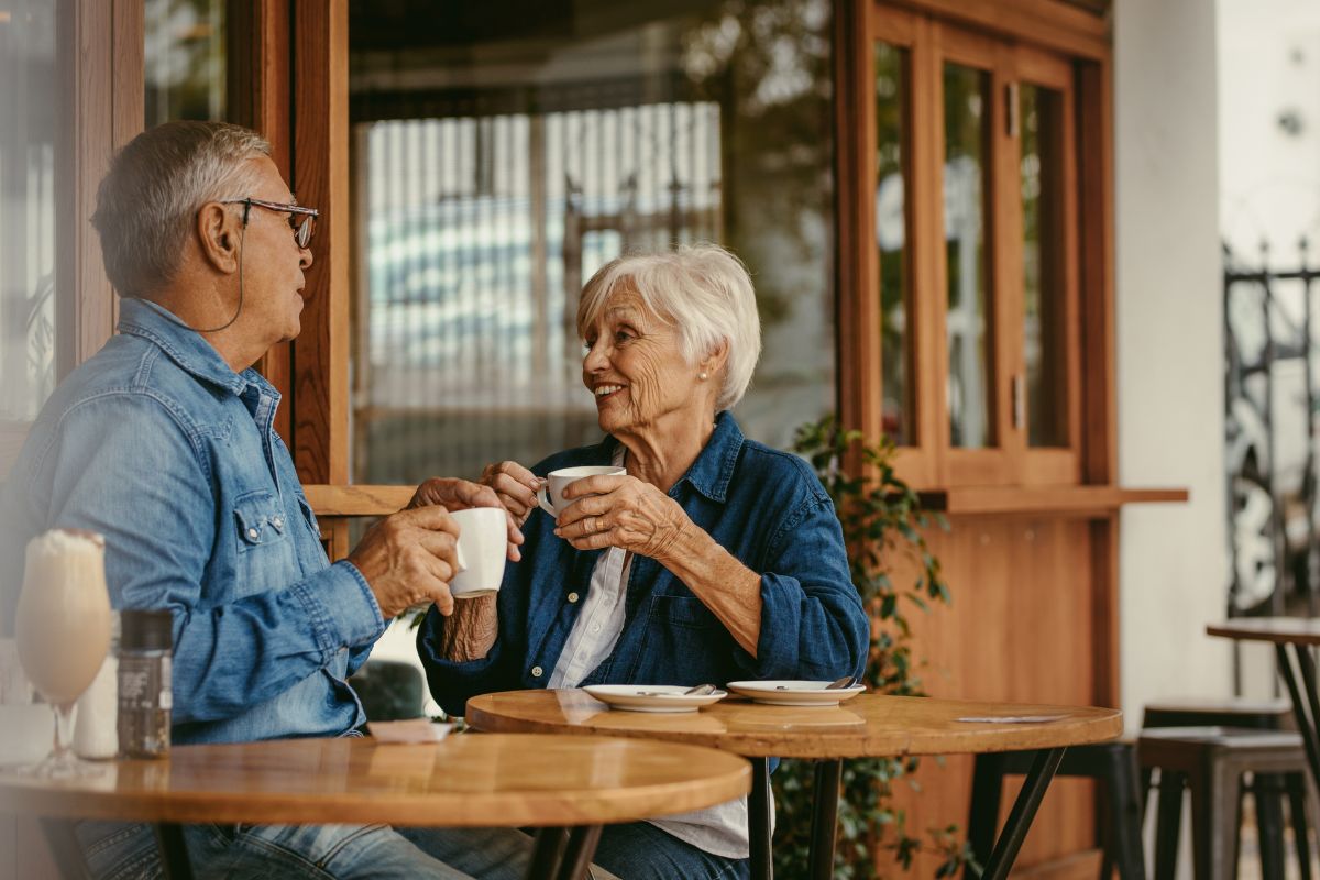 Senior couple enjoying a coffee together at an outdoor cafe.