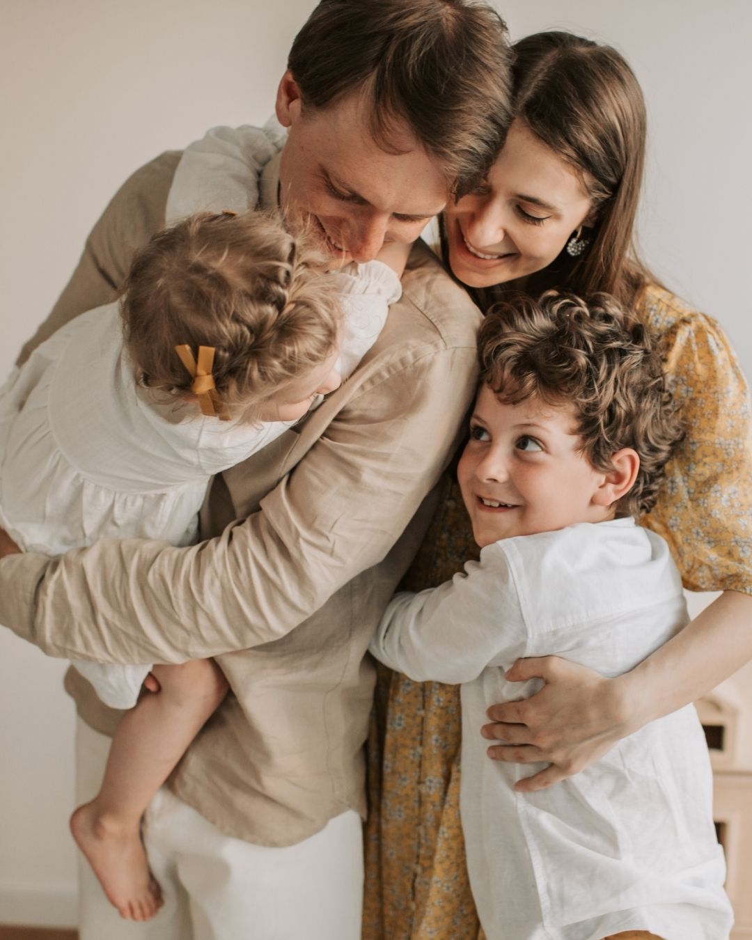 Family of four embracing each other indoors