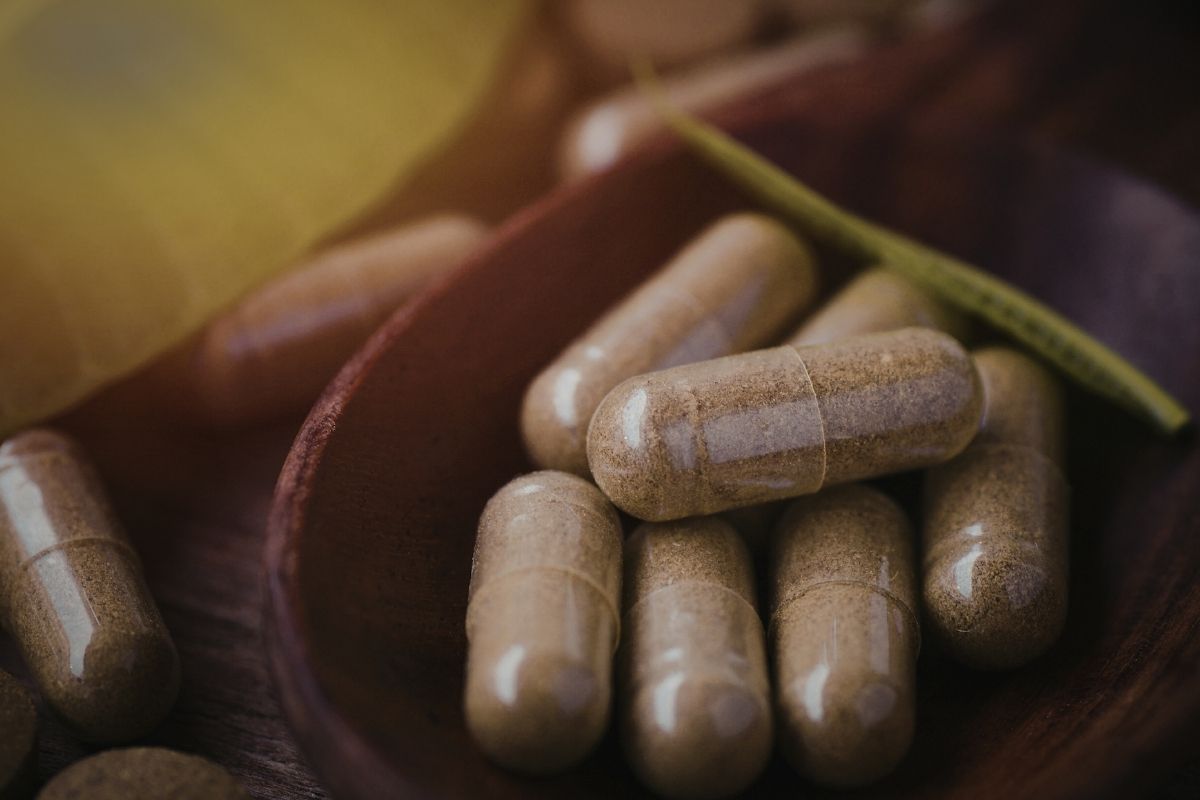 Brown capsules on a wooden spoon with a blurred background