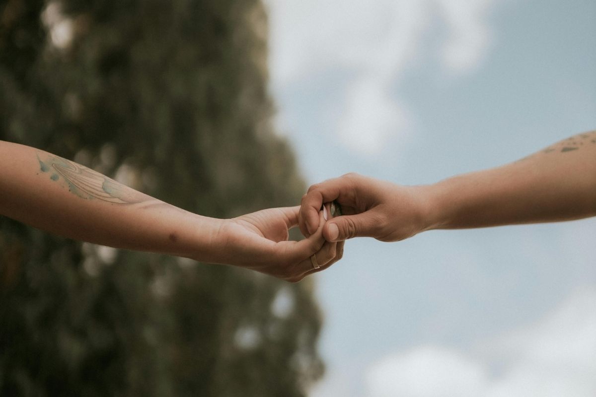 Two people holding hands with a blurred natural background